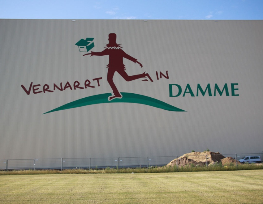 Das Logo „Vernarrt in Damme“ ziert eine Außenwand des Hochregallagers, der Narr ist 18 m hoch
